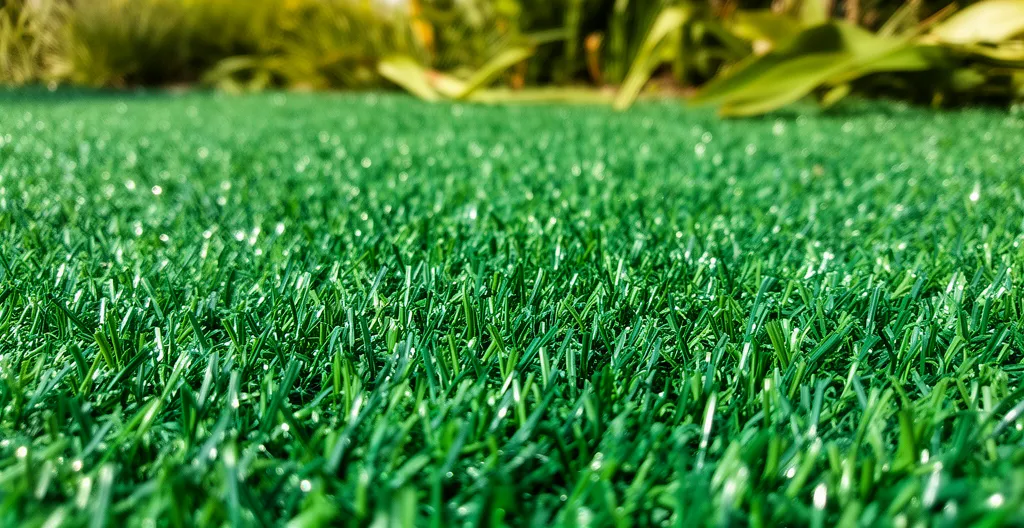 Gros plan sur fibres de gazon synthétique montrant leur couleur vive sous la lumière naturelle